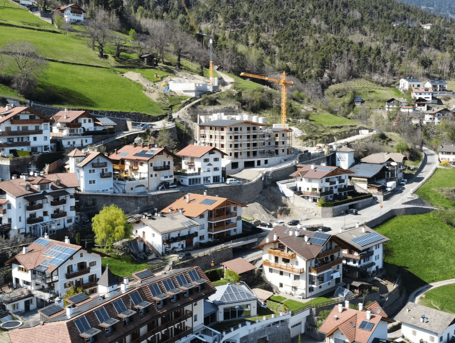 Luftaufnahme eines Dorfes in den Bergen mit einem Neubauprojekt in der Bauphase.