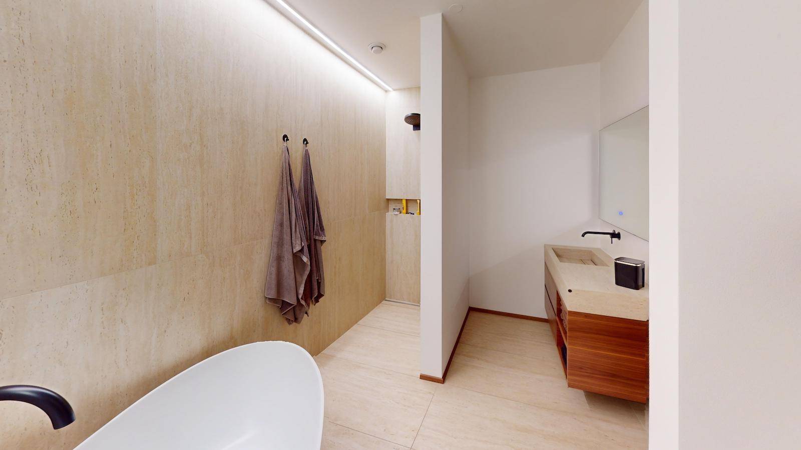 Modernes Badezimmer mit freistehender Badewanne, Dusche und Natursteinfliesen.