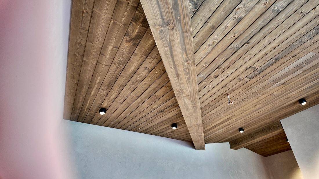 Detailaufnahme einer rustikalen Holzbalkendecke mit integrierten modernen Deckenspots.