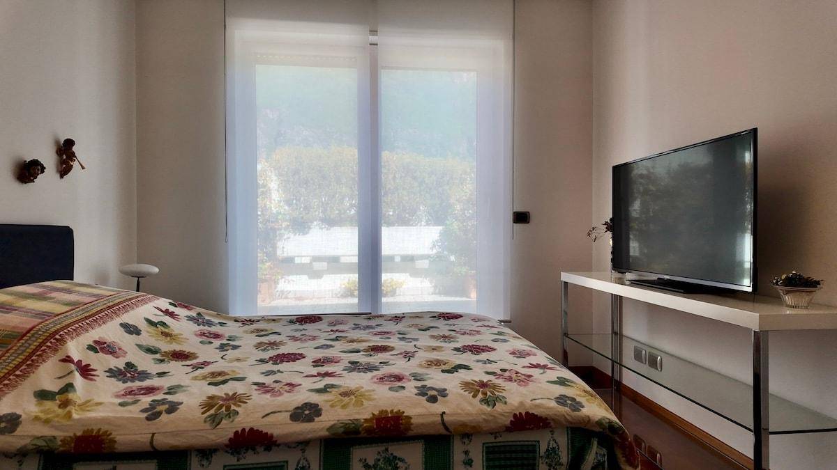 Schlafzimmer mit Holzboden, Fernseher und Fenster mit Blick auf die Umgebung.