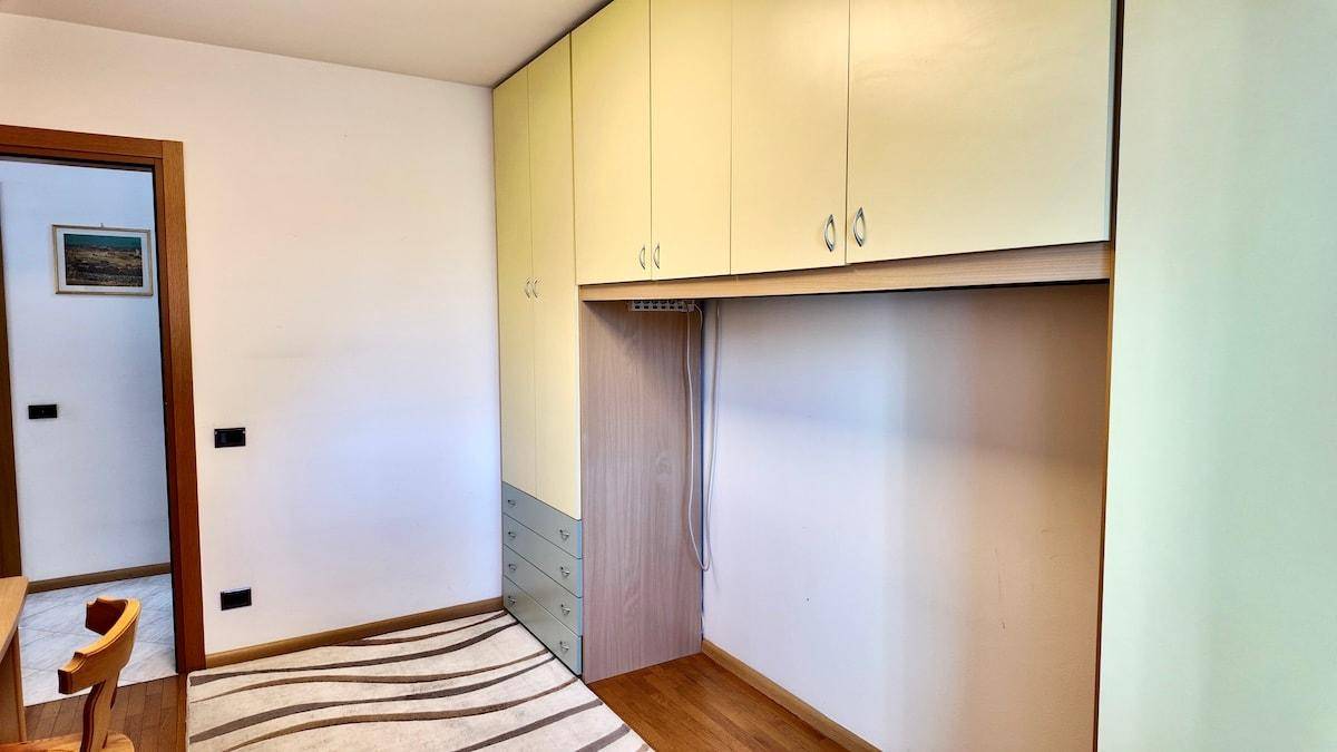 Schlafzimmer mit Einbauschränken, Holzfußboden und Teppich mit Muster.