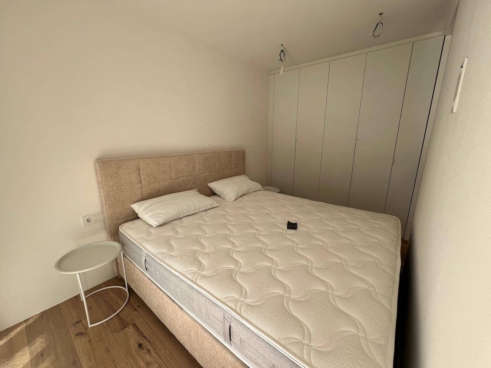 Schlafzimmer mit beigem Bett und raumhohen weißen Einbauschränken für optimale Platzausnutzung.