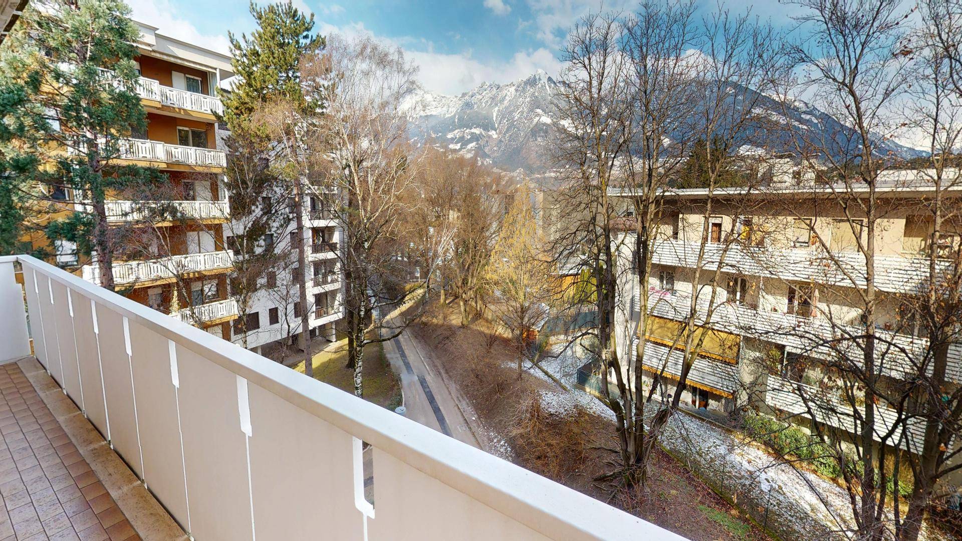 Balkon mit Blick auf die umliegenden Bäume und Gebäude.