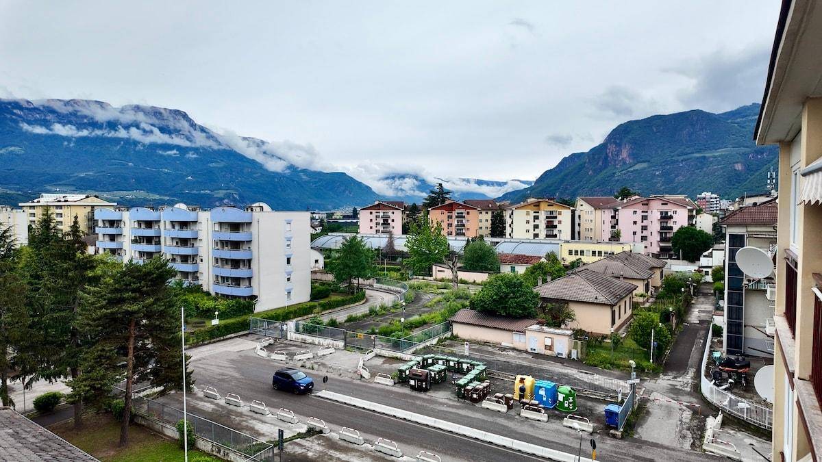 Panoramablick auf ein Wohngebiet mit Straße, Gebäuden und Bergen im Hintergrund.