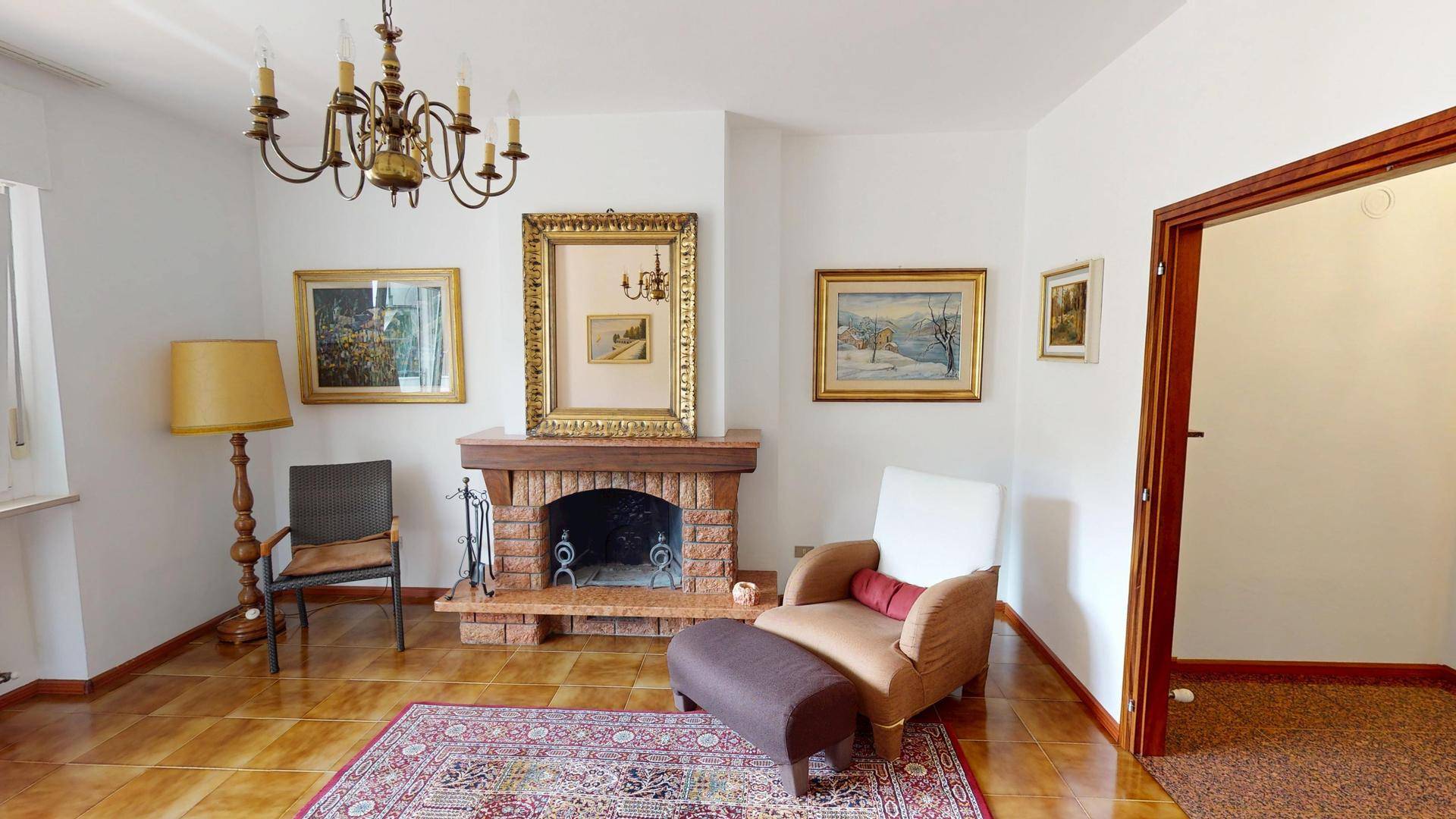 Gemütliches Wohnzimmer mit traditionellem Kamin, Fliesenboden und klassischer Einrichtung.