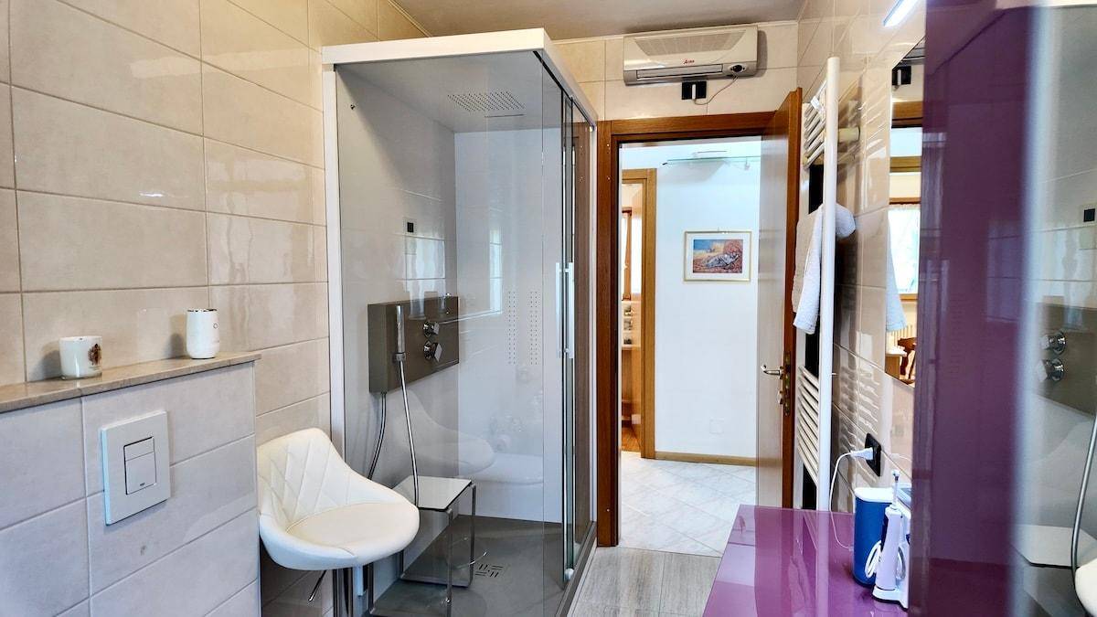 Badezimmer mit Duschkabine, Fliesen und Klimaanlage über der Tür.