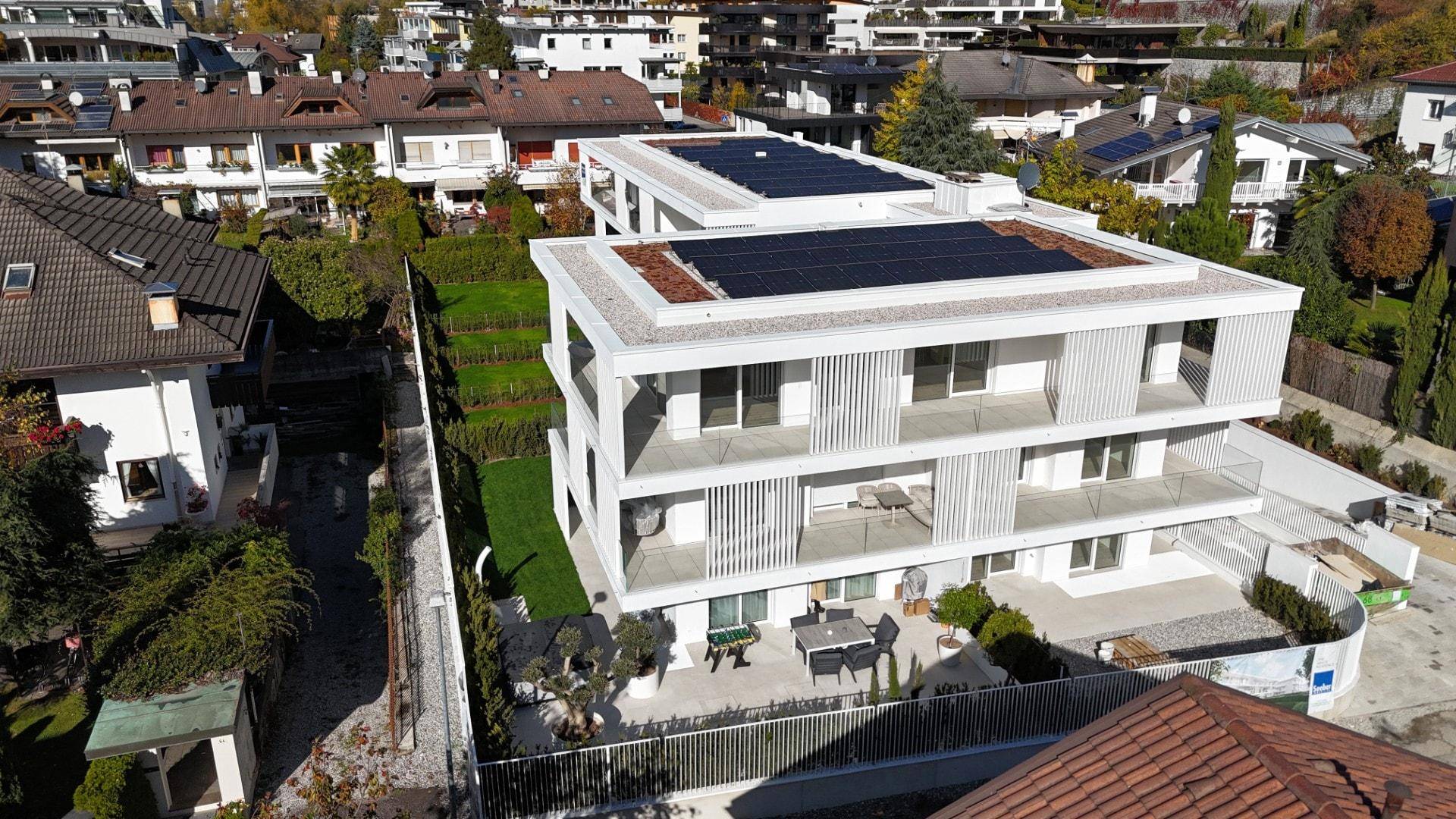 Übersicht des Neubaus aus der Vogelperspektive mit großzügigen Außenbereichen und Solaranlage.