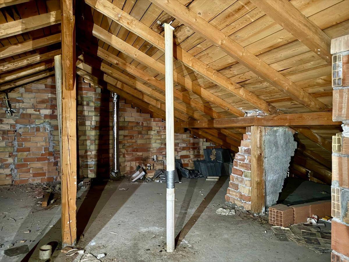 Geräumiger Dachboden mit freiliegenden Holzbalken und Ziegelwänden, ideal für zukünftige Erweiterungen.