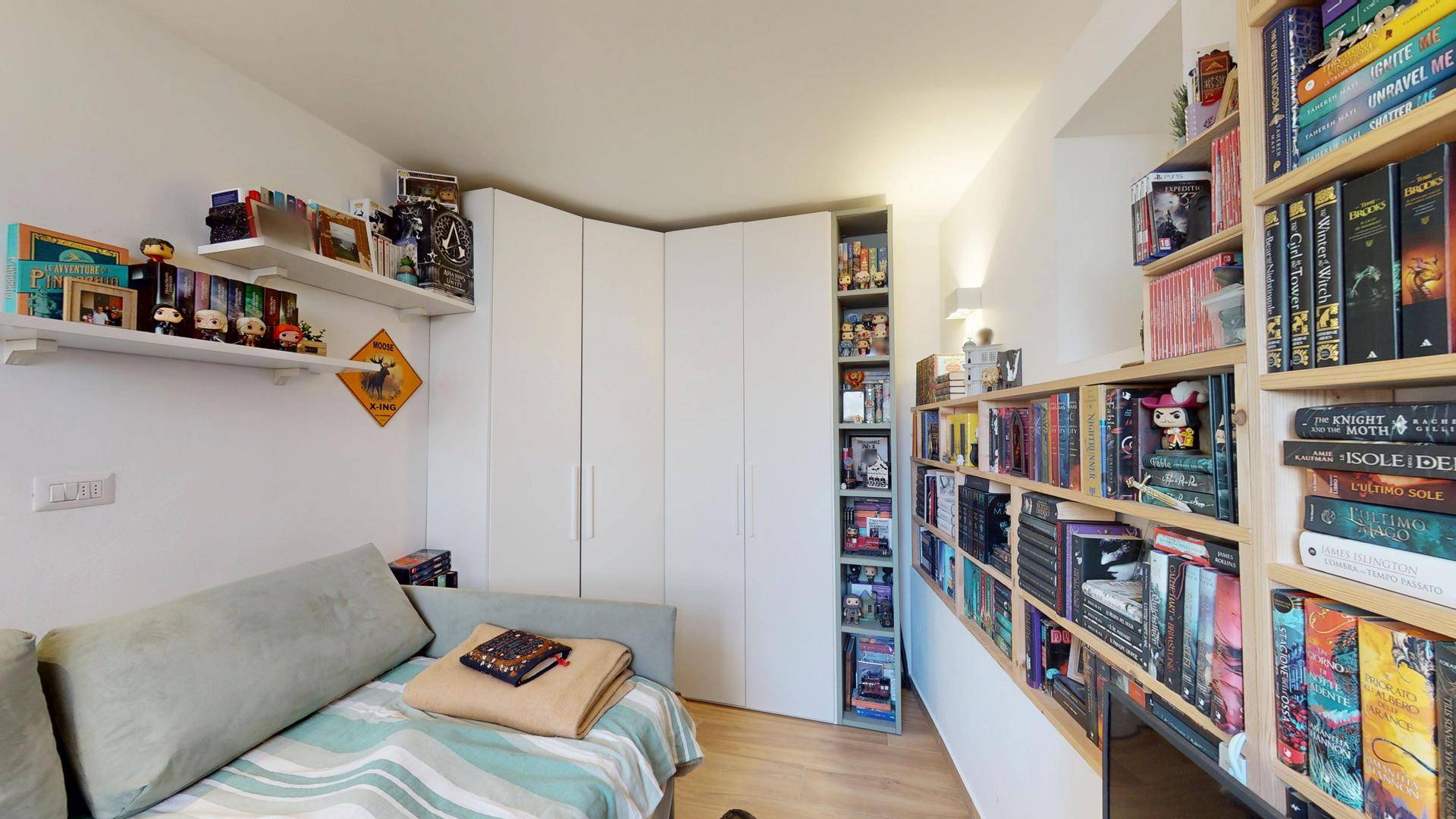 Wohnbereich mit umfangreichem Bücherregal, Sofa und Einbauschränken.