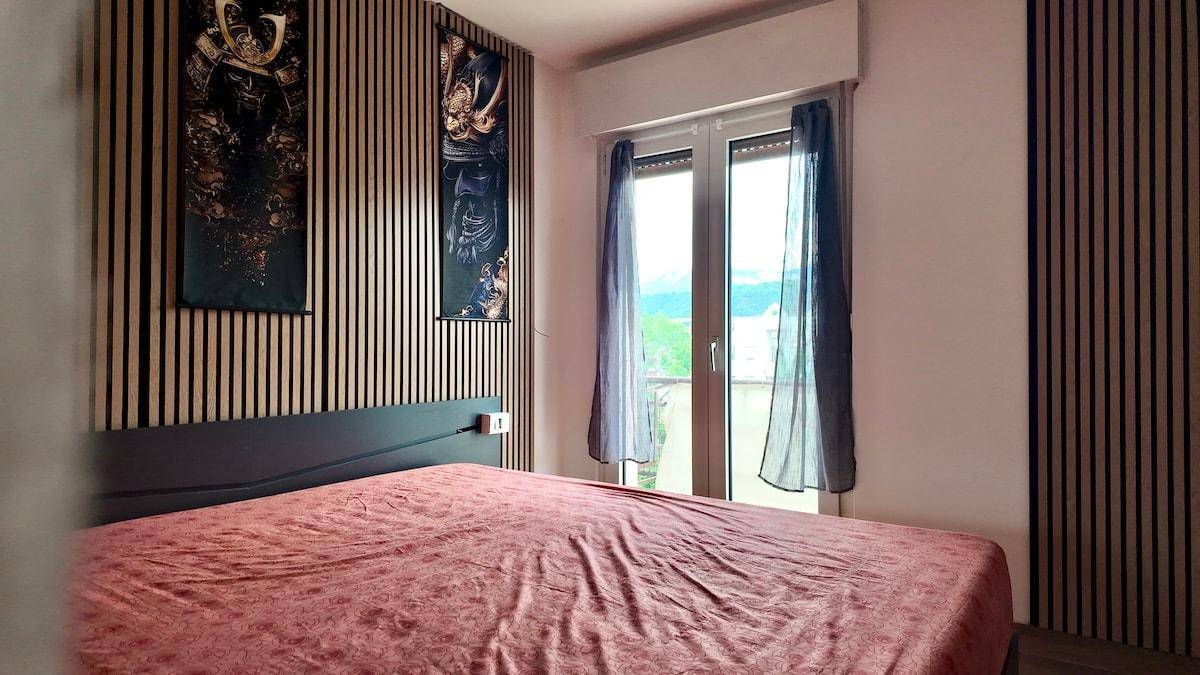 Schlafzimmer mit Holzwandverkleidung, großem Bett und Fenster mit Bergblick.