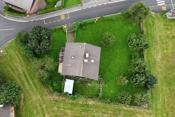 Draufsicht auf das Hausgrundstück mit Garten, Dach und angrenzenden Wegen.