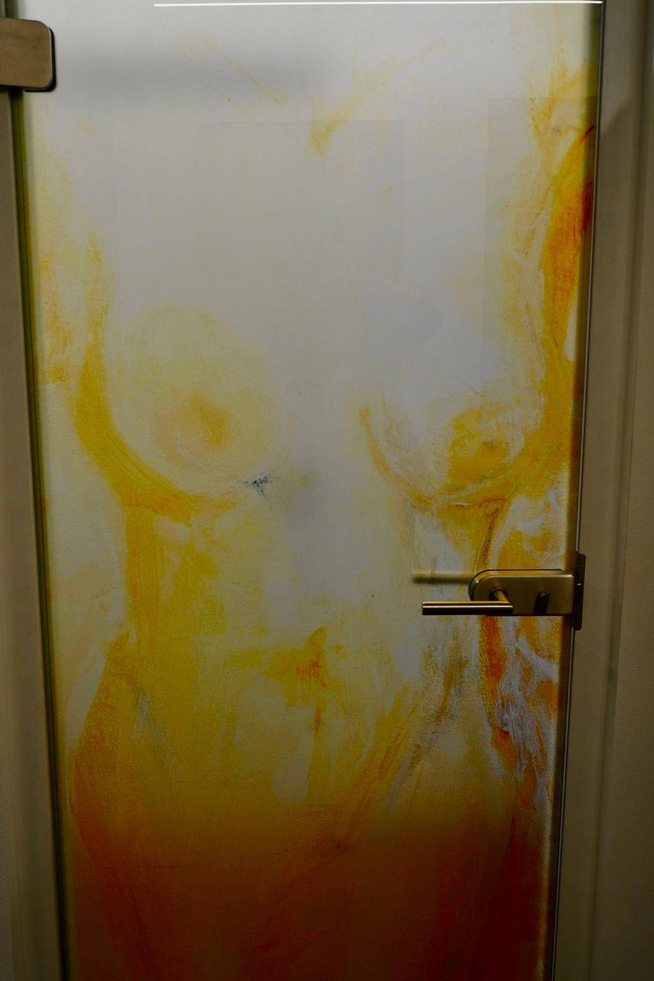 Eine geschlossene Tür mit abstrakten gelb-orangen Mustern in einem Innenraum.
