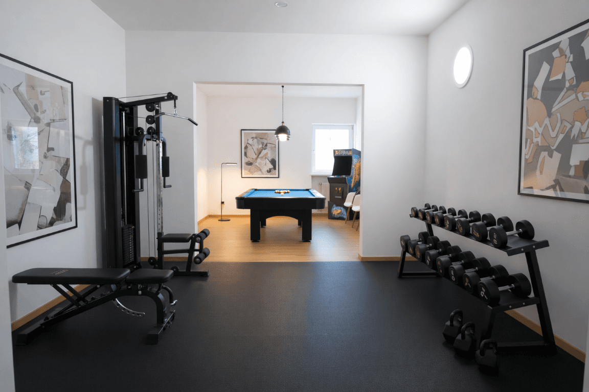Fitness- und Spielzimmer mit Trainingsgeräten, Hanteln und Billardtisch.