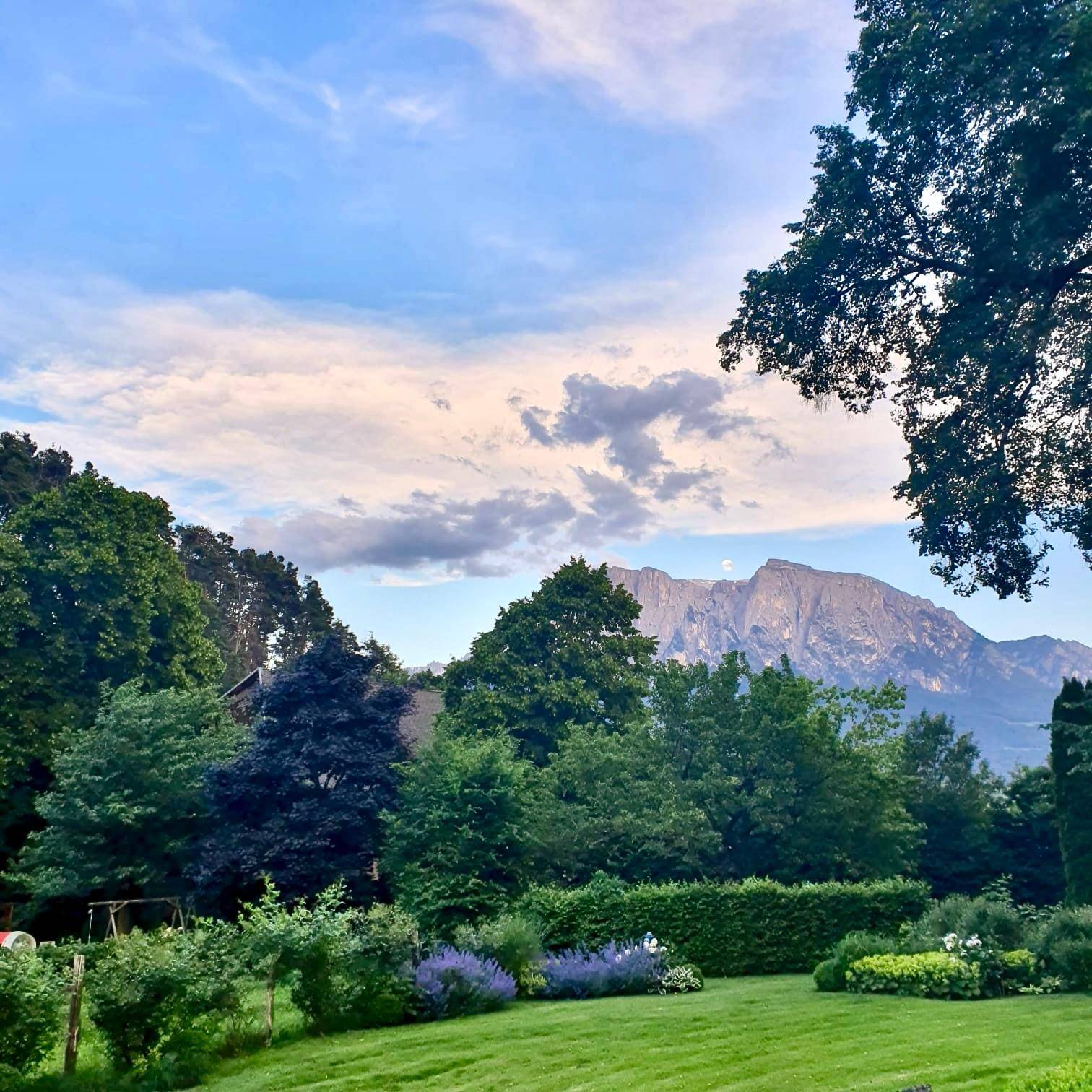 Malerischer Garten mit üppigem Grün, gepflegtem Rasen und einem atemberaubenden Blick auf die umliegenden Berge.