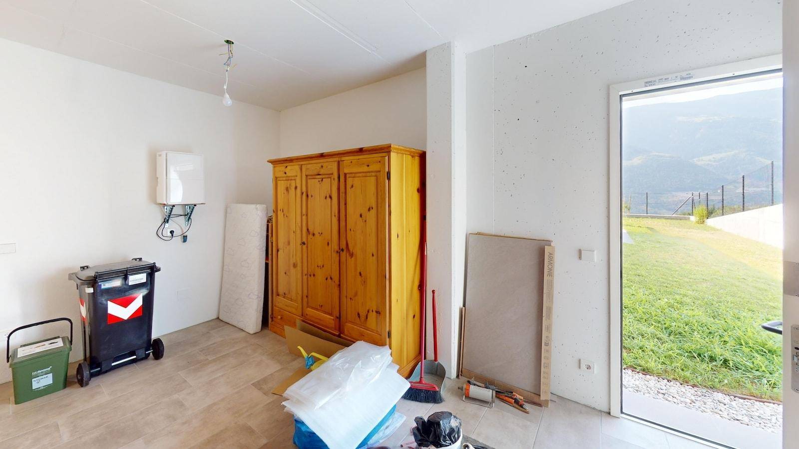 Abstellraum mit Fliesenboden, Holzschrank und direktem Zugang zum Außenbereich mit Bergblick.