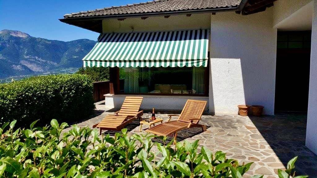 Gemütliche Steinterrasse mit Sonnenliegen und Markise, ideal zum Entspannen im Freien.