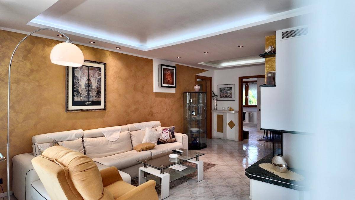 Geräumiges Wohnzimmer mit beiger Couch, Stehlampe und dekorativer Wandgestaltung.