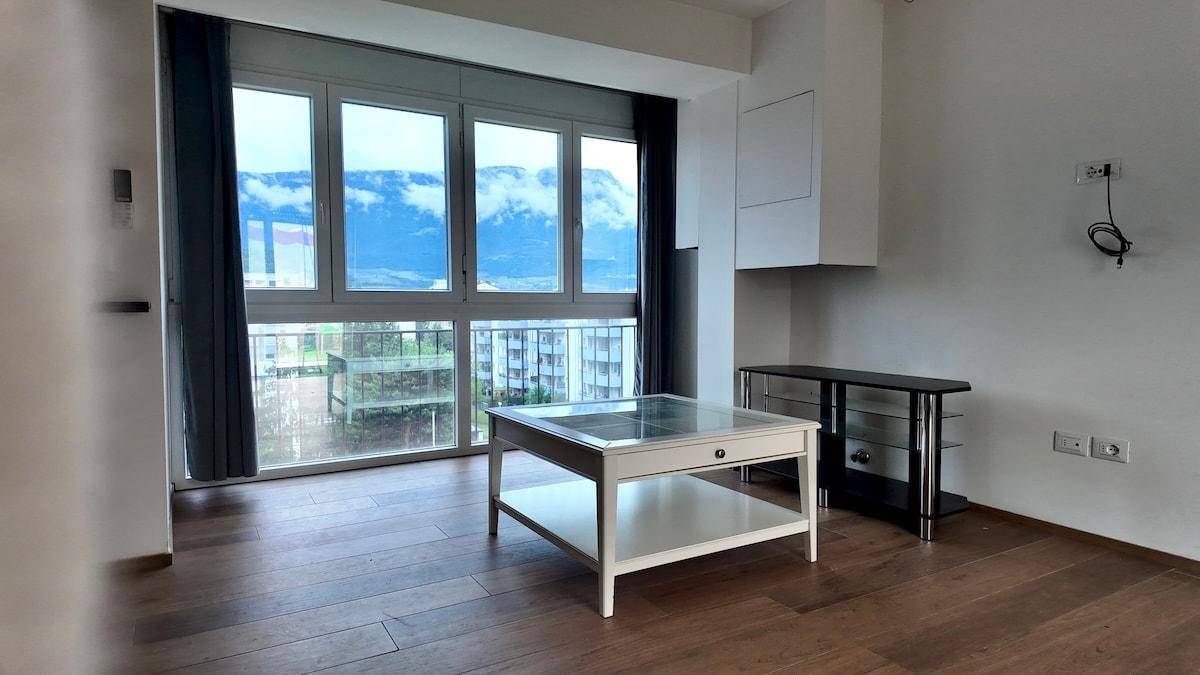 Geräumiger Wohnbereich mit großen Fenstern und Panoramablick auf die Berge.