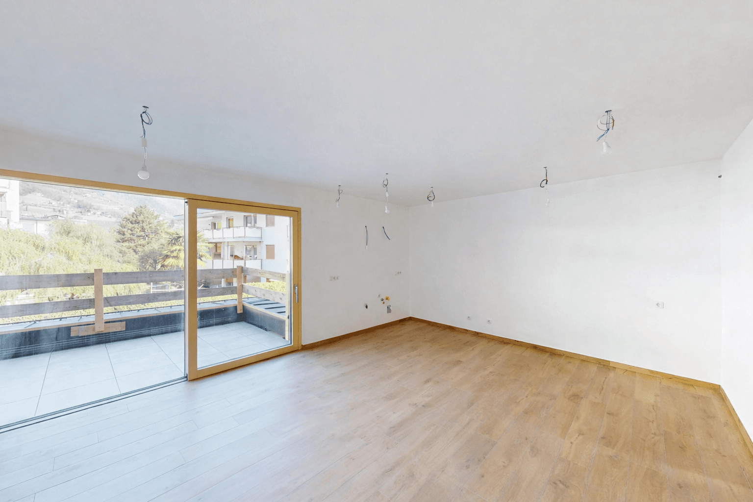 Lichtdurchfluteter Wohnbereich mit großem Schiebefenster und Zugang zu einer Außenterrasse.