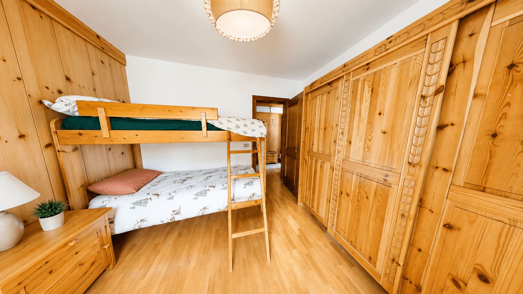 Gemütliches Schlafzimmer mit Etagenbett, Holzvertäfelung und geräumigen Einbauschränken.