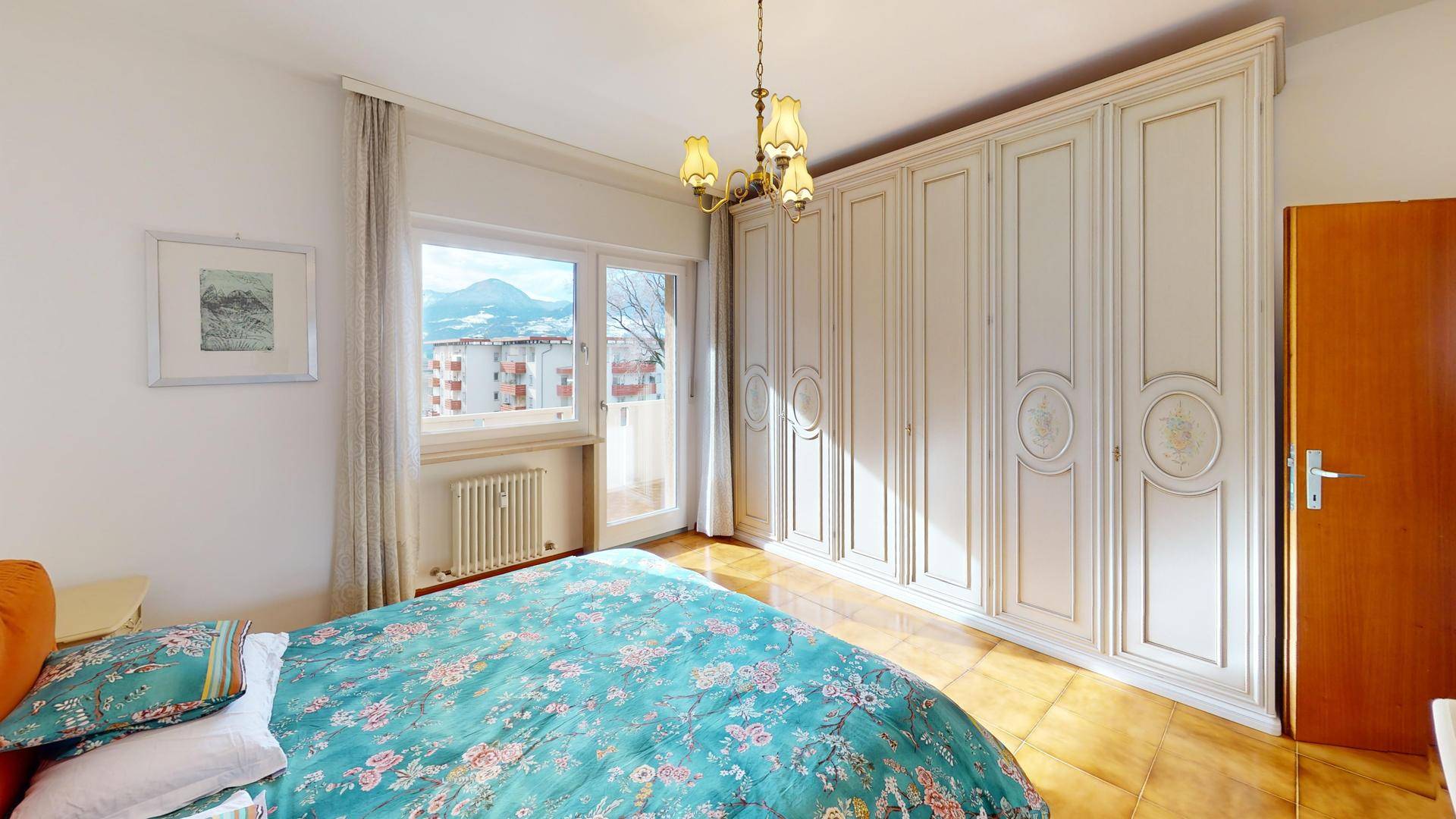 Schlafzimmer mit großem Einbauschrank, Doppelbett und Balkonzugang.