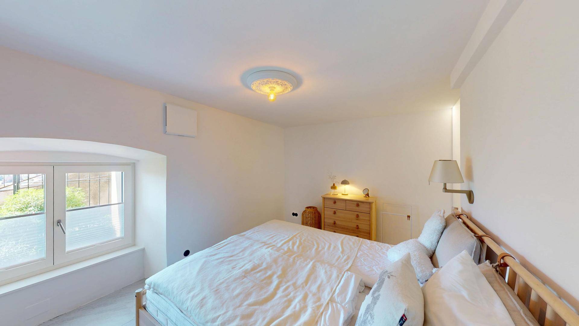 Helles Schlafzimmer mit Doppelbett, Holzmöbeln und einem Fenster mit Ausblick.