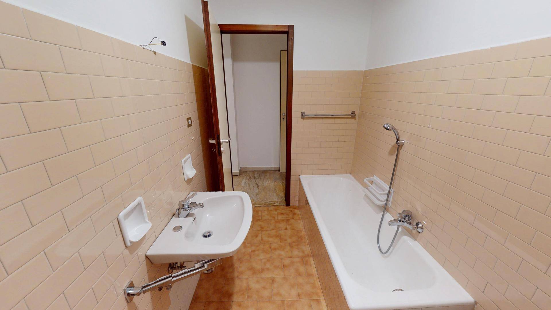 Badezimmer mit Badewanne, Waschbecken und beigefarbenen Fliesen, typisch für die 80er Jahre.