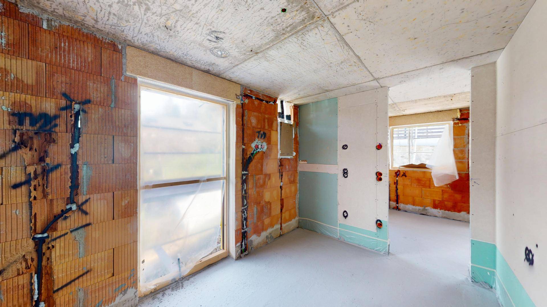 Rohbauzimmer mit Ziegelwänden und Fenstern, die viel Tageslicht hereinlassen.