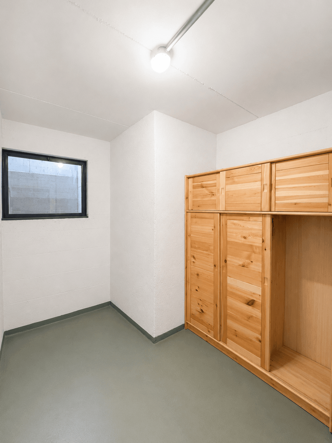 Praktischer Abstellraum mit kleinem Fenster und eingebautem Holzschrank.