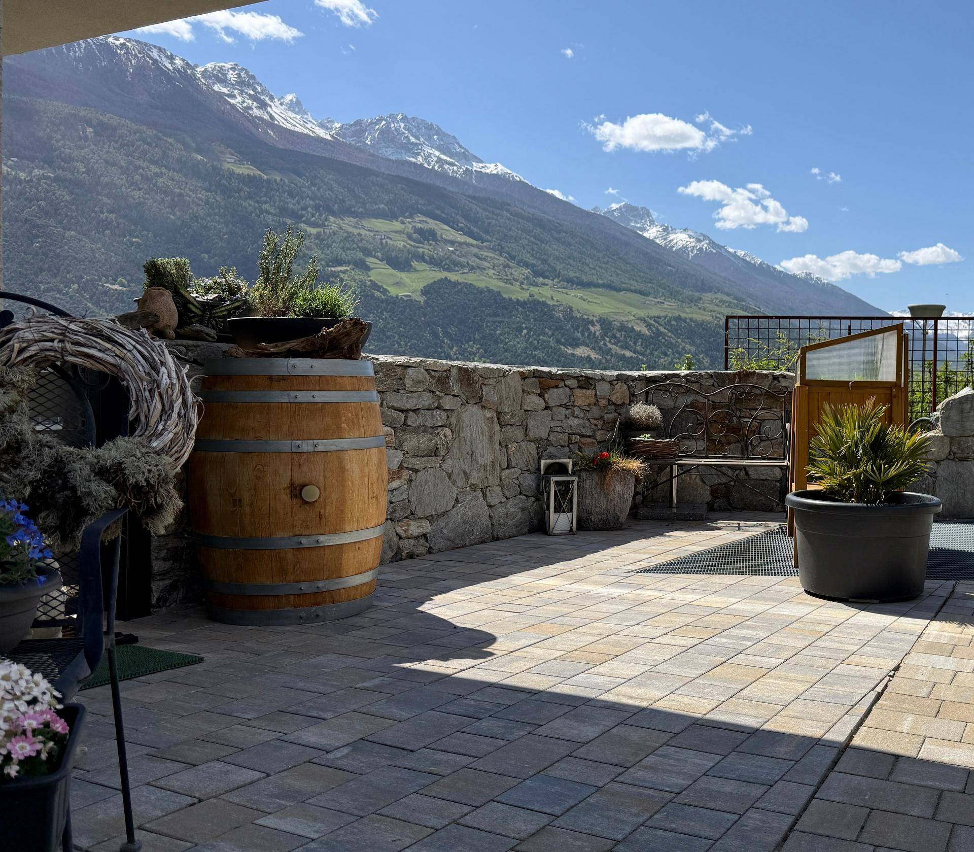 Geräumige Terrasse mit Steinpflaster, rustikaler Steinmauer und beeindruckendem Bergblick.