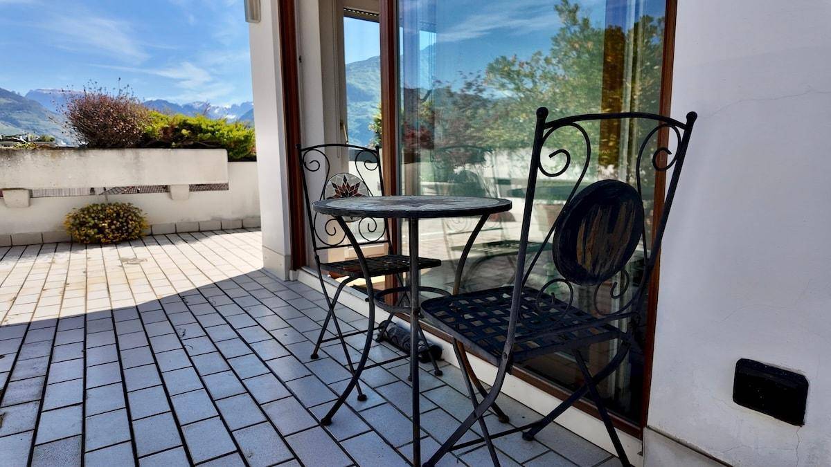 Sonniger Terrassenbereich mit schmiedeeisernen Möbeln und weitem Bergblick.