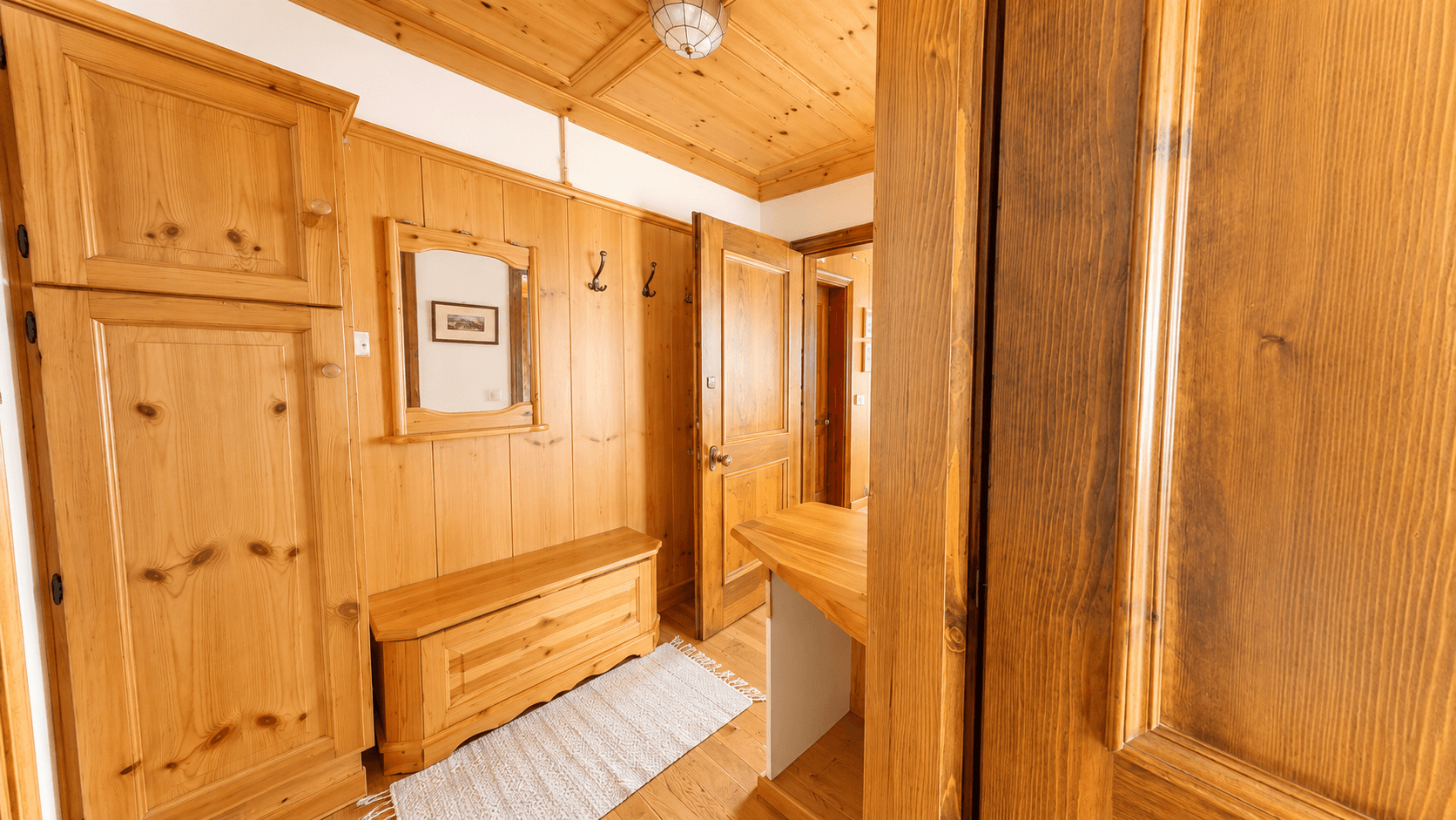 Traditioneller Flur mit Holzvertäfelung, Garderobe und rustikalen Möbeln.