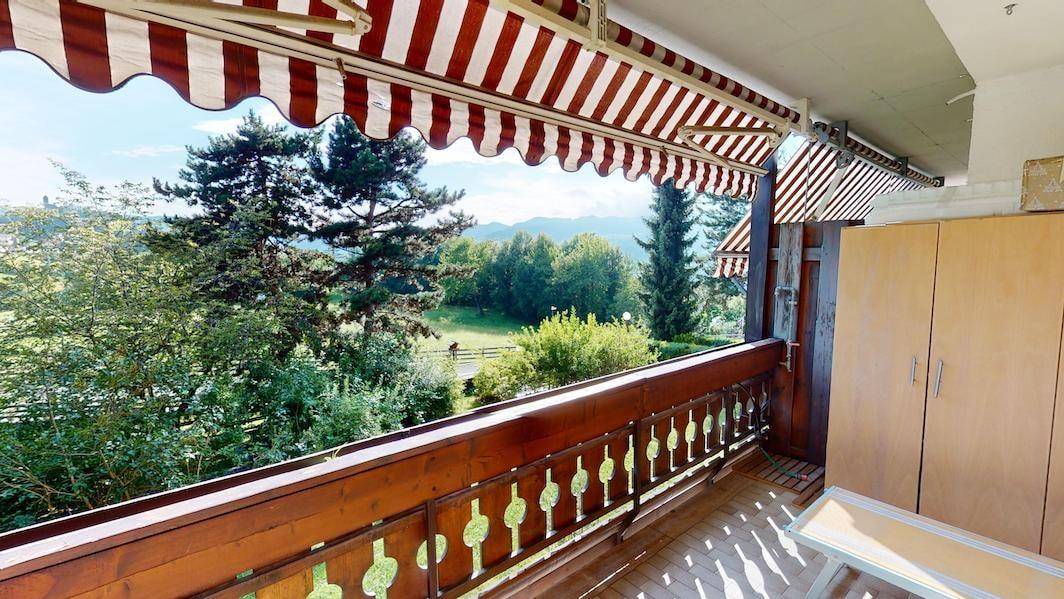 Sonniger Balkon mit Markise, Holzbalkon und Panoramablick auf die Landschaft.