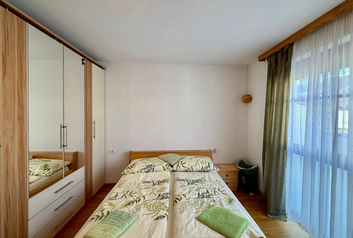 Helles Schlafzimmer mit Doppelbett, Spiegelschränken und Zugang zu einem Außenbereich.