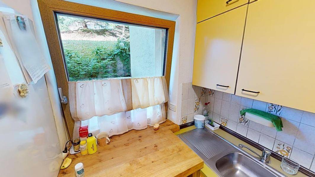 Helle Küche mit Fenster, Holzarbeitsplatte und Blick ins Grüne.