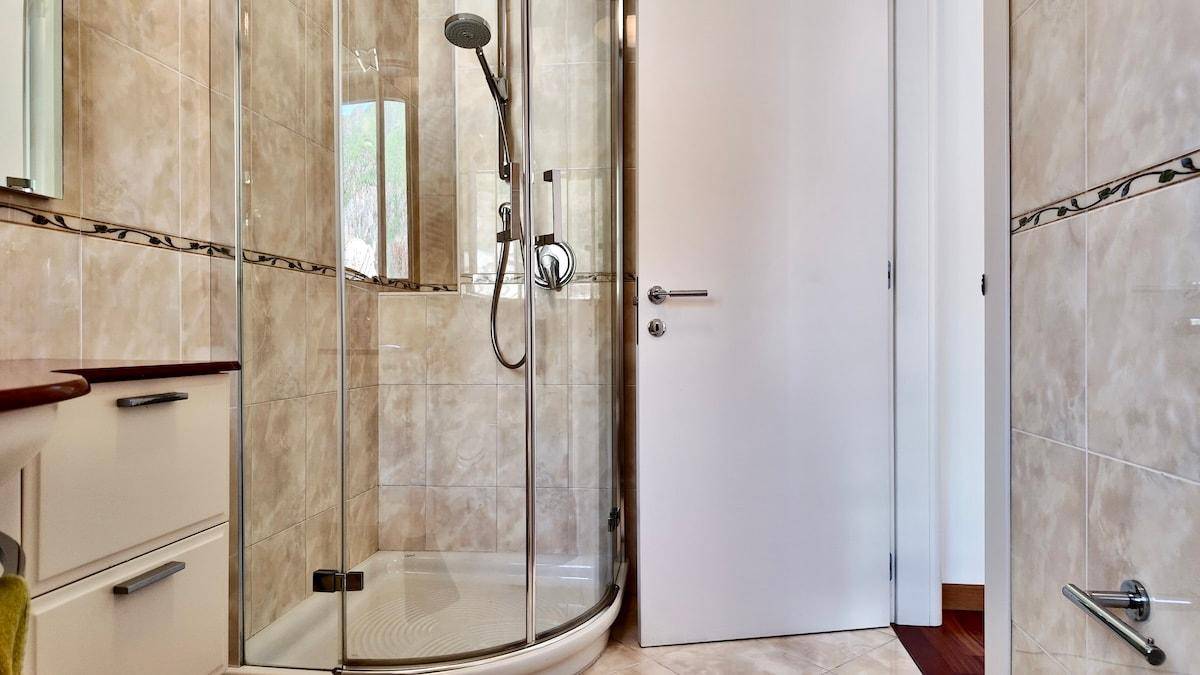 Modernes Badezimmer mit Duschkabine, beigefarbenen Fliesen und Fenster.