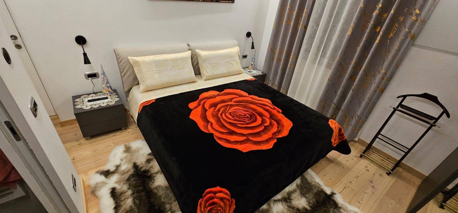 Modernes Schlafzimmer mit Doppelbett, Nachttischen und dekorativer Deckenbeleuchtung.