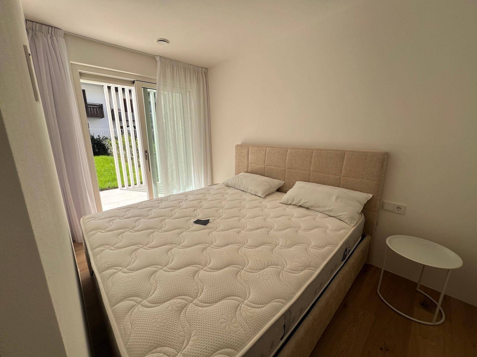 Schlafzimmer mit Doppelbett und direktem Zugang zu einer kleinen Terrasse und dem Garten.