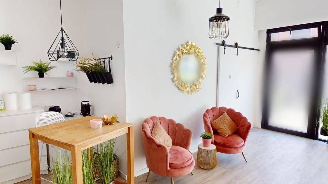 Gemütliche Sitzecke mit Samtsesseln, einem Holztisch und dekorativen Pflanzen.