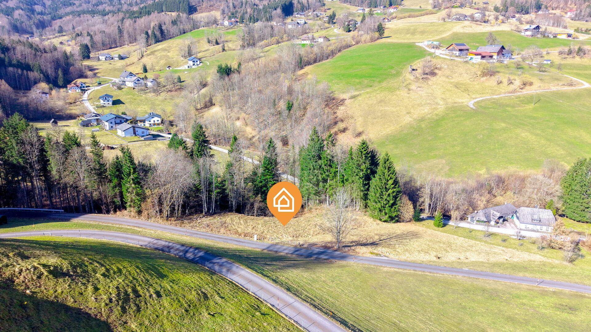 Luftaufnahme einer malerischen Landschaft mit einem markierten Standort für ein potenzielles Zuhause.