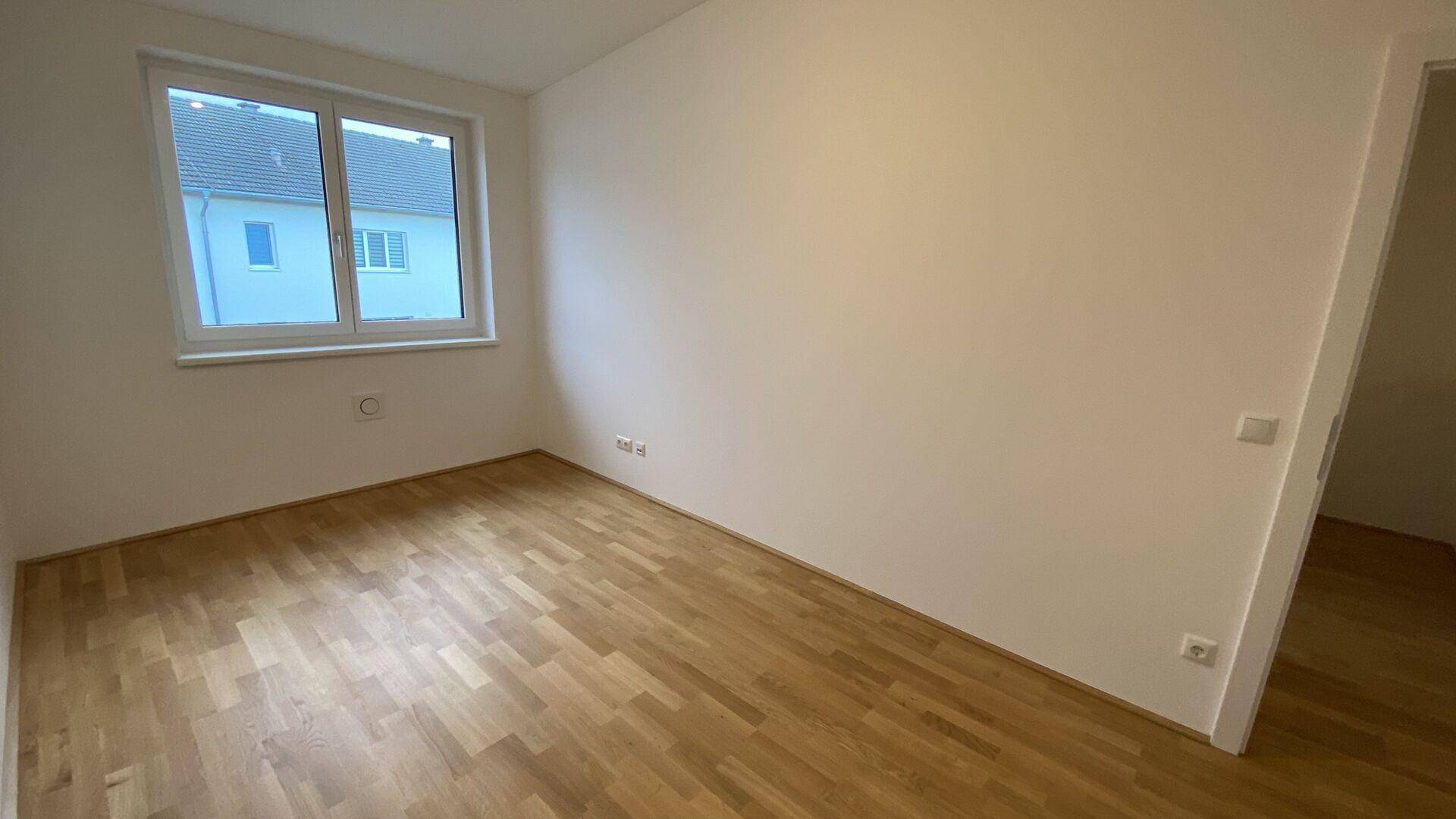 Lichtdurchflutetes Zimmer mit Parkettboden und Ausblick, ideal als Kinderzimmer.