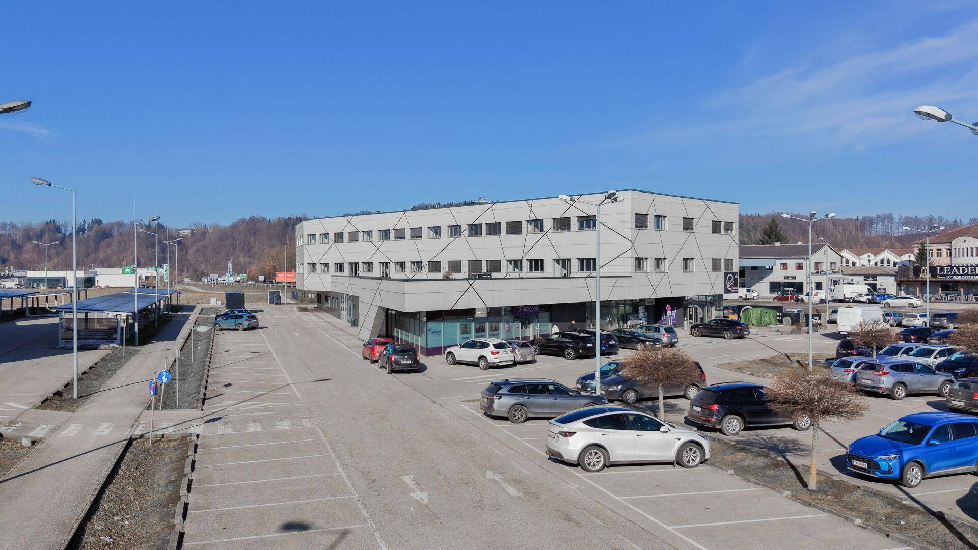 Ansicht eines modernen Geschäftsgebäudes mit vielen Parkplätzen unter blauem Himmel.