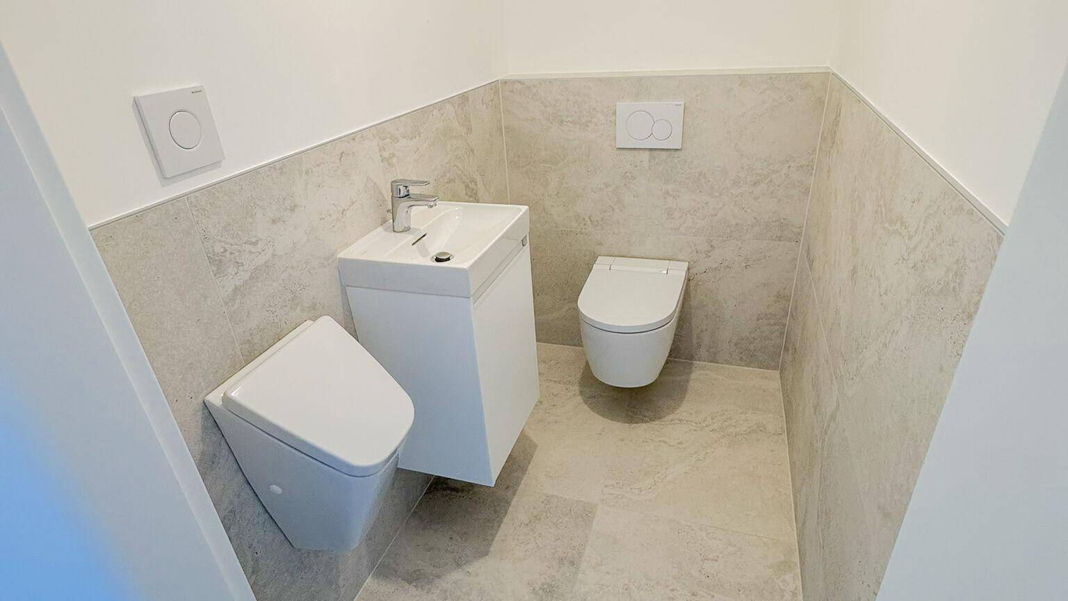 Kleines Gäste-WC mit modernen Fliesen, wandhängendem WC und kleinem Waschbecken.