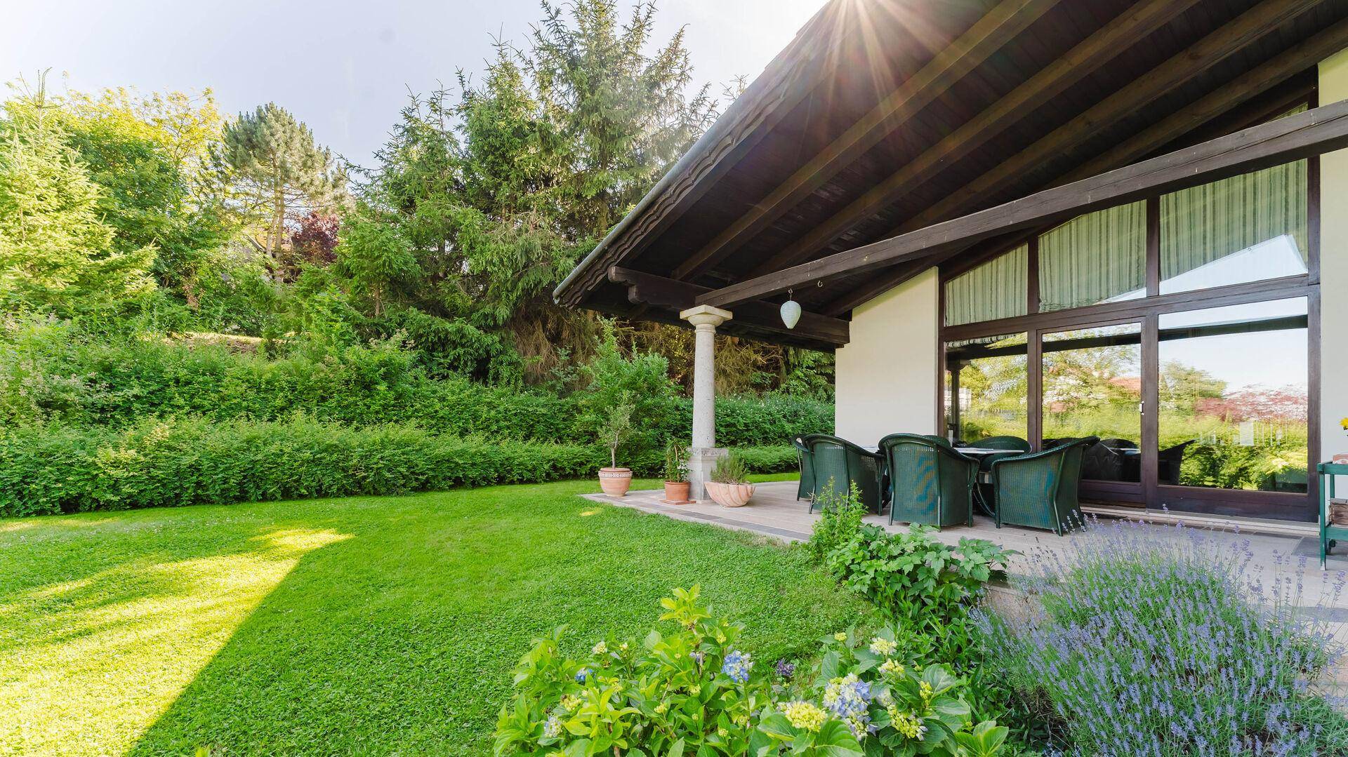Überdachte Terrasse mit Sitzgelegenheiten und Blick in den grünen Garten.