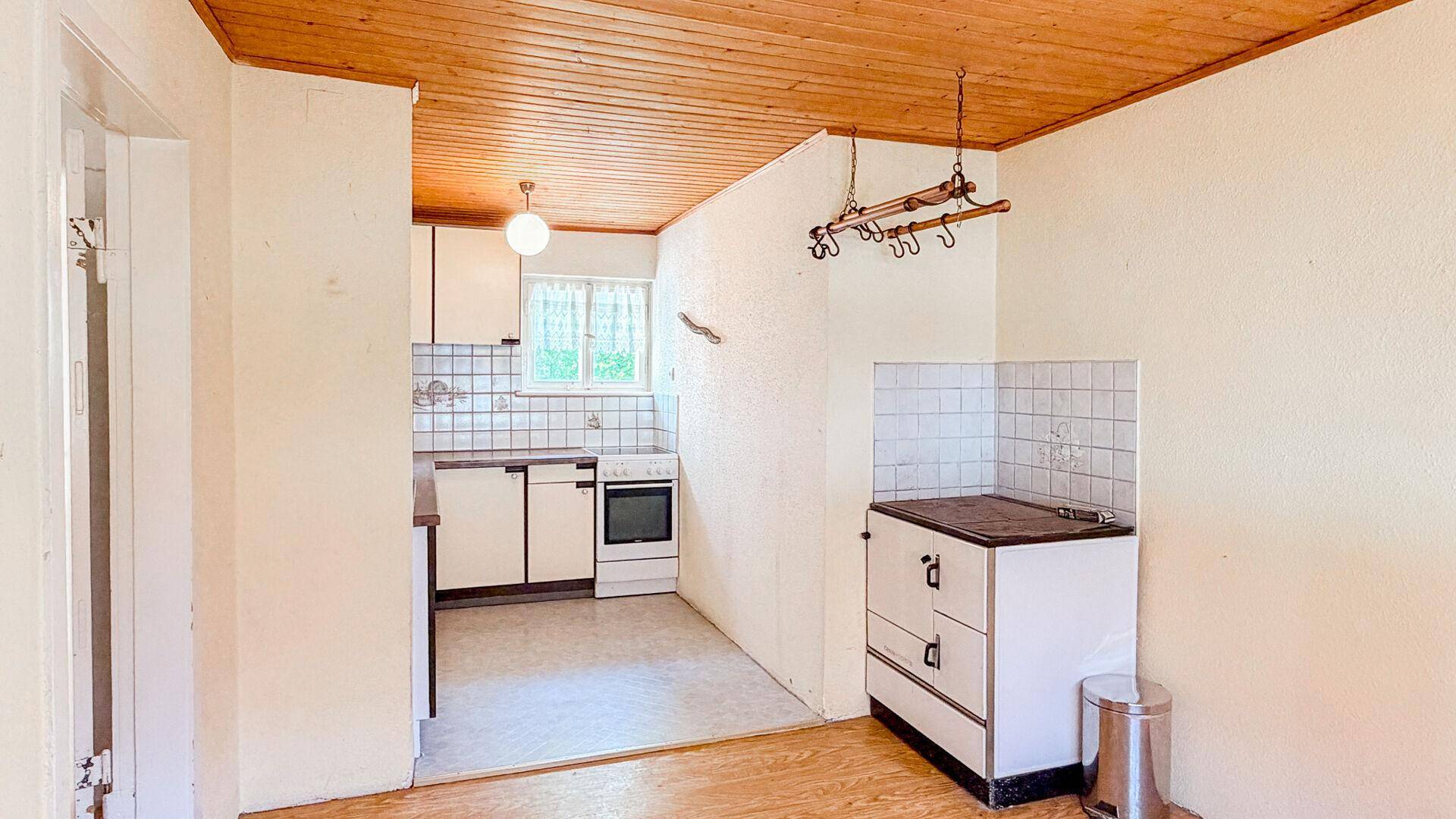 Küche mit traditionellem Ofen, weißen Fliesen und Holzdecke, bereit zur Modernisierung.