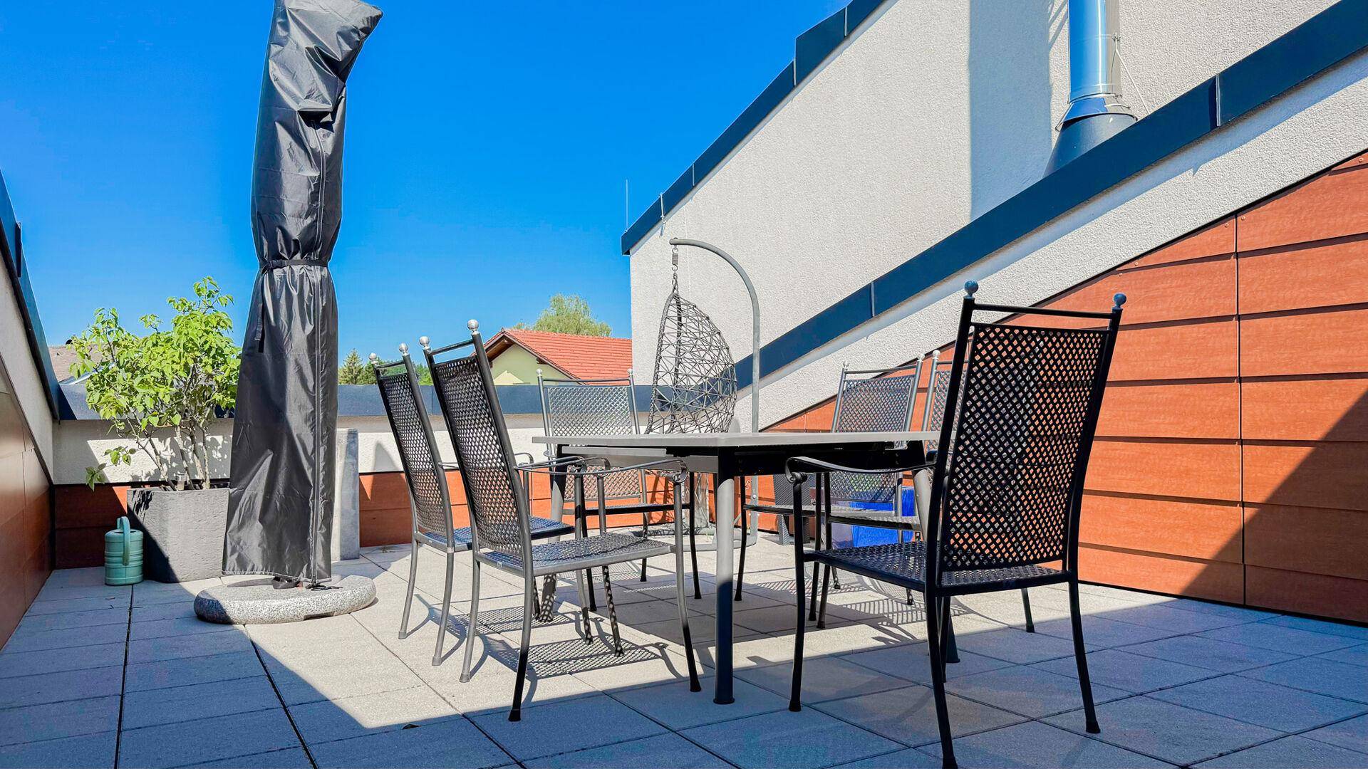 Geräumige Dachterrasse mit Esstisch und Stühlen, ideal für Mahlzeiten im Freien.