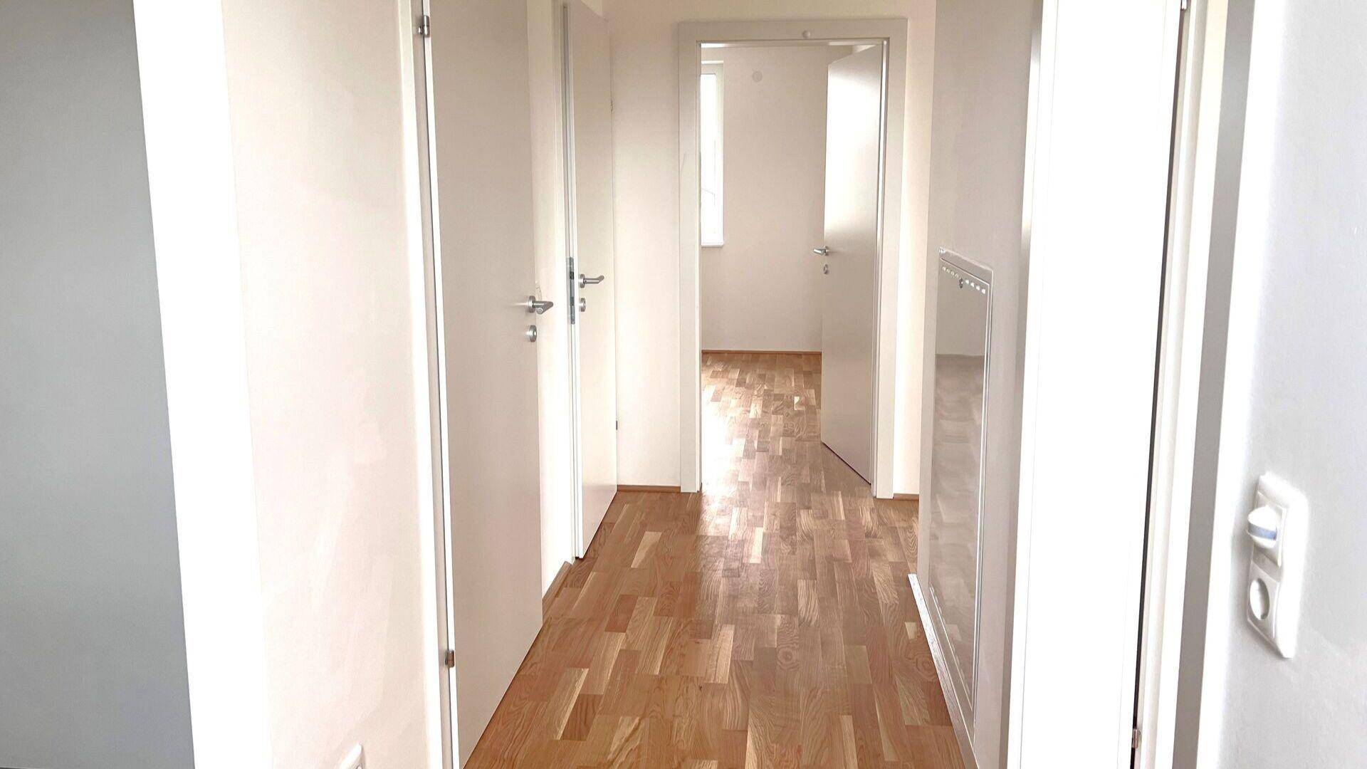 Heller Flur mit Holzboden und mehreren Türen, der zu verschiedenen Räumen führt.