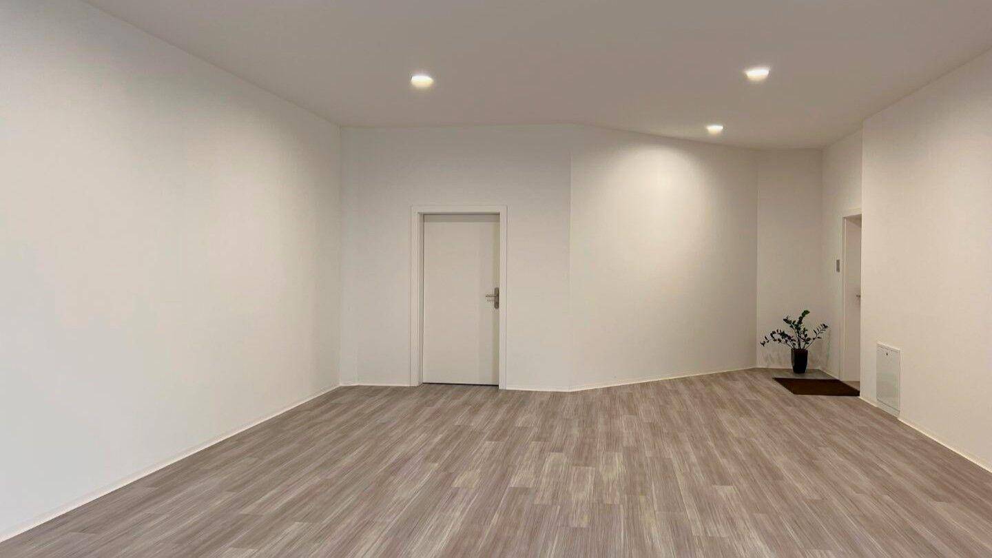 Moderner, leerer Raum mit hellem Vinylboden und Einbaustrahlern in der Decke.