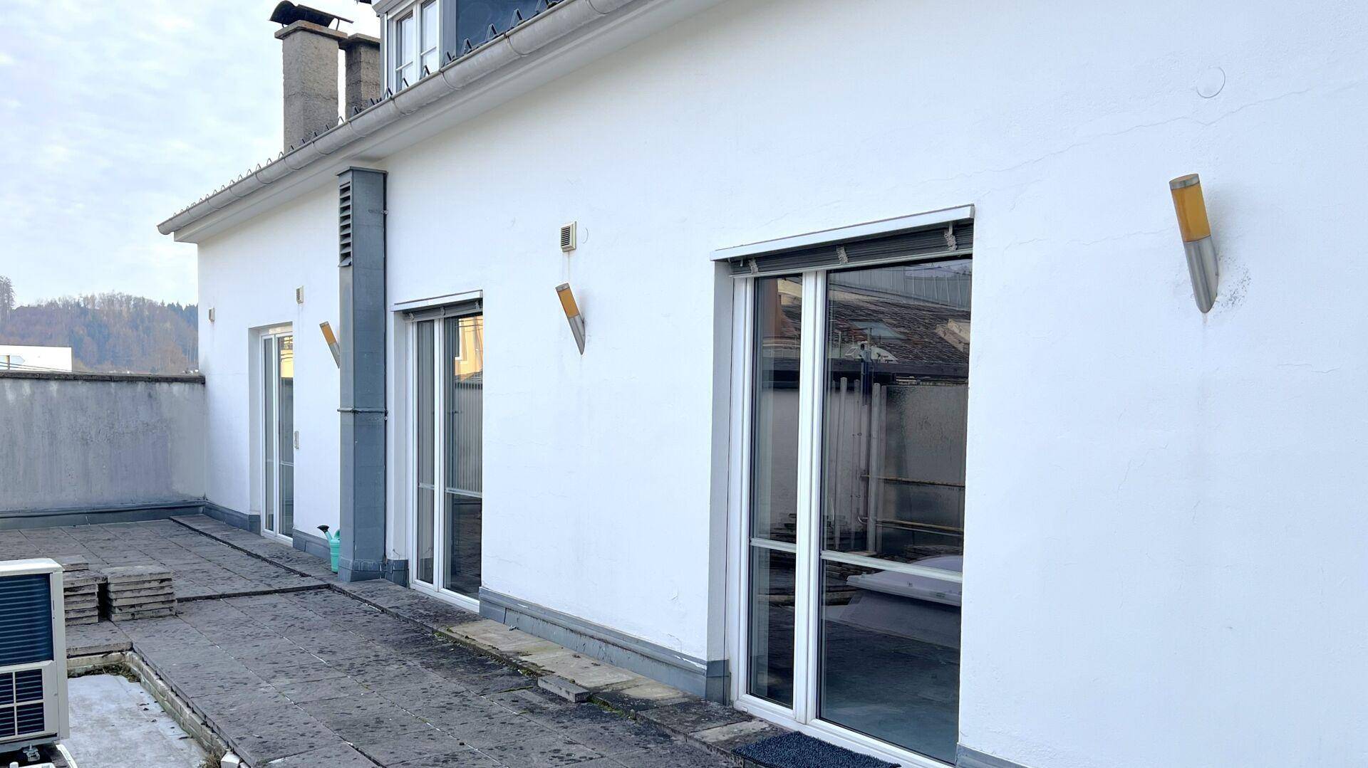 Große Dachterrasse mit Schiebetüren zum Innenbereich und einer Klimaanlage im Freien.