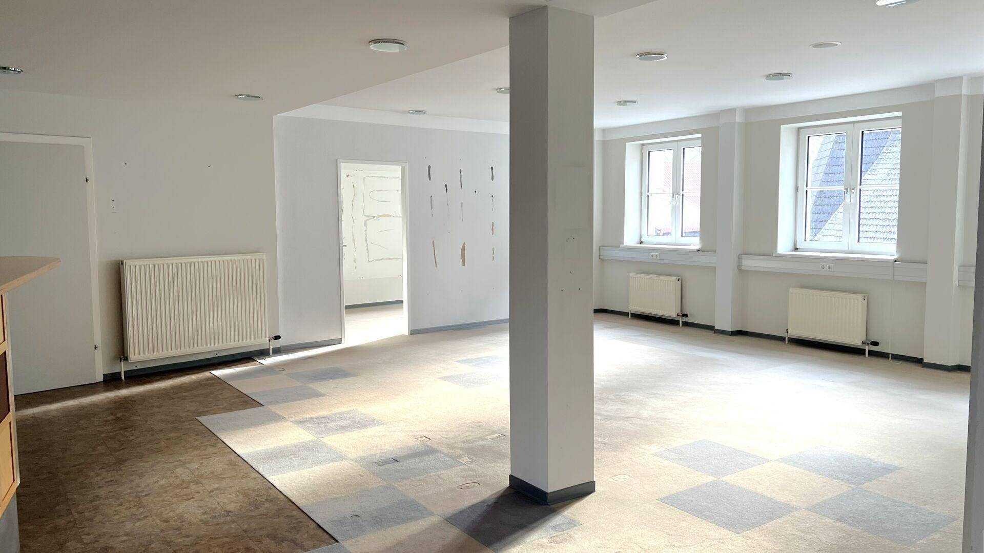 Geräumiger, heller Raum mit tragender Säule und großen Fenstern, die viel Tageslicht hereinlassen.